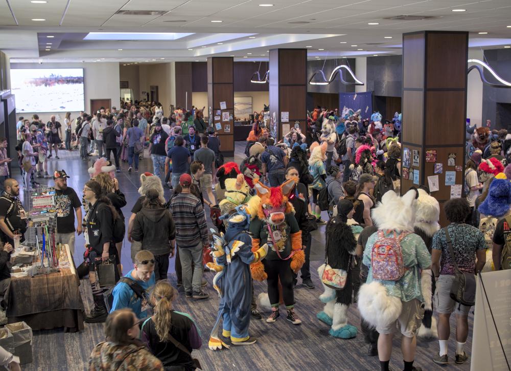 A picture of a common area of the convention floor. There's a lot of people in a relatively small space, with a lot of fursuiters